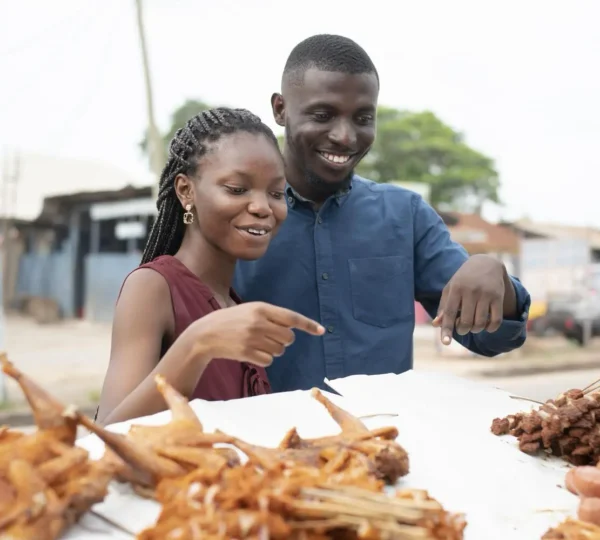 Couple sharing Nigerian suya at a roadside vendor, showing the communal spirit of Lagos street food. 