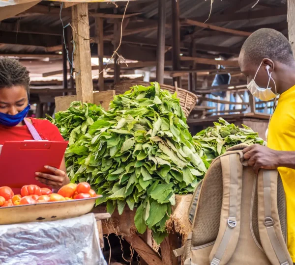 A man buying fresh vegetables from a vendor at Mile 12 Market, one of the largest local markets in Lagos.