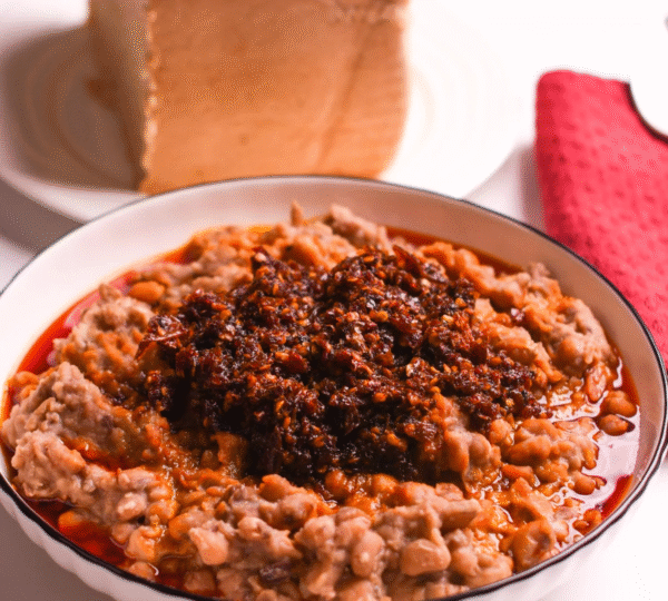 A serving of Ewa Agoyin beans paired with soft Agege bread, a beloved and nostalgic Lagos street food breakfast.