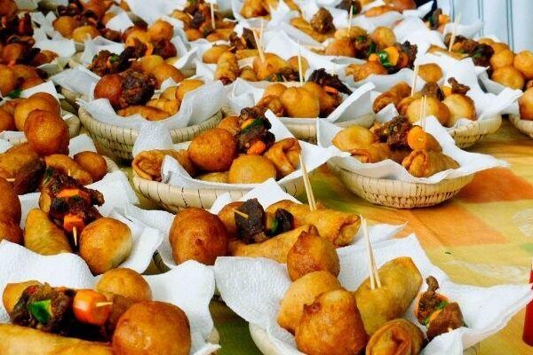 Baskets of assorted small chops including puff-puff, samosas, and gizzard skewers, a popular party and Lagos street food snack.