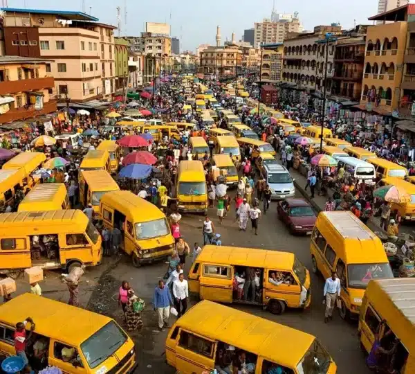 Street view of Lagos Mainland with yellow danfo buses and market vendors during a food tour in Lagos Nigeria.