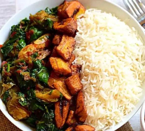 A plate of Ofada rice served with vegetables and fried plantain, highlighting culinary innovation driving Nigerian food industry jobs.