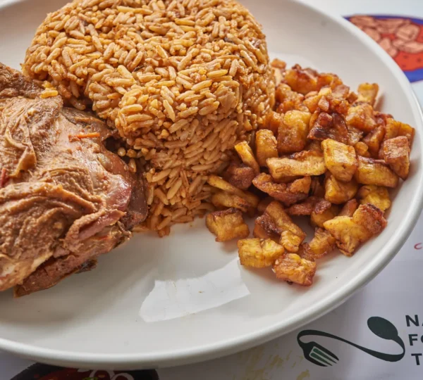 Jollof rice served with fried plantain and beef — a staple among Nigerian foods that define Lagos culture, loved for its smoky flavor and festive aroma.