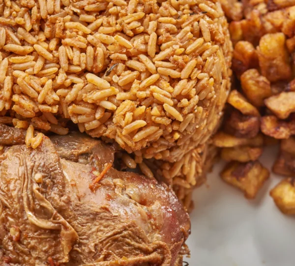 Nigerian Jollof Rice served with fried plantain and meat — a colorful side dish often paired with Fufu and Egusi Soup during Naija Food Tour experiences.