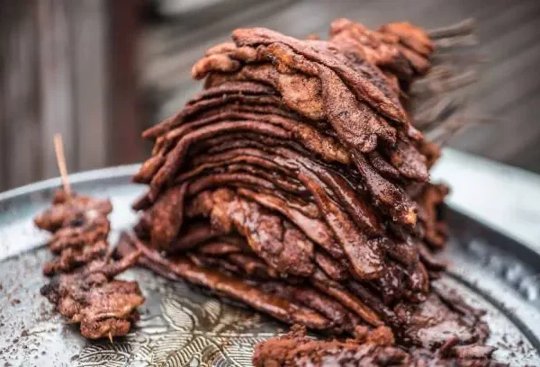Spicy beef suya stacked on a tray at University of Suya, a famous roadside restaurant in Lagos Nigeria.