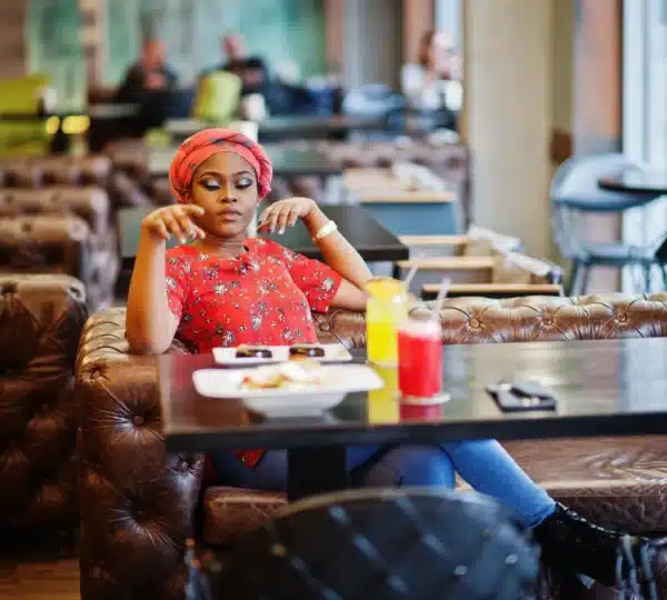 A young woman enjoying a meal at a Lagos restaurant, symbolizing urban growth and new Nigerian food industry jobs.